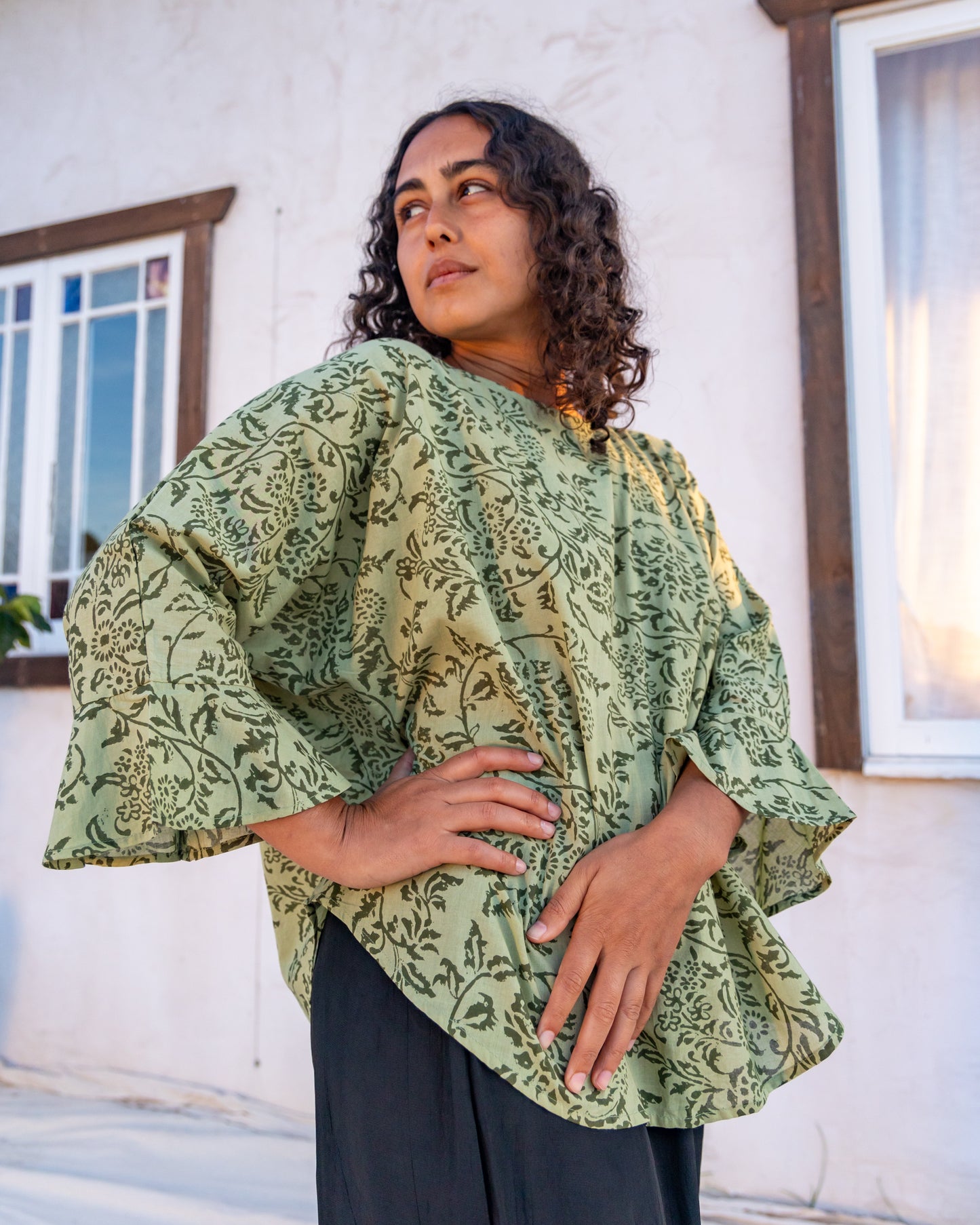 woman dressed in boa flared top in gooseberry print standing in front of a white wall