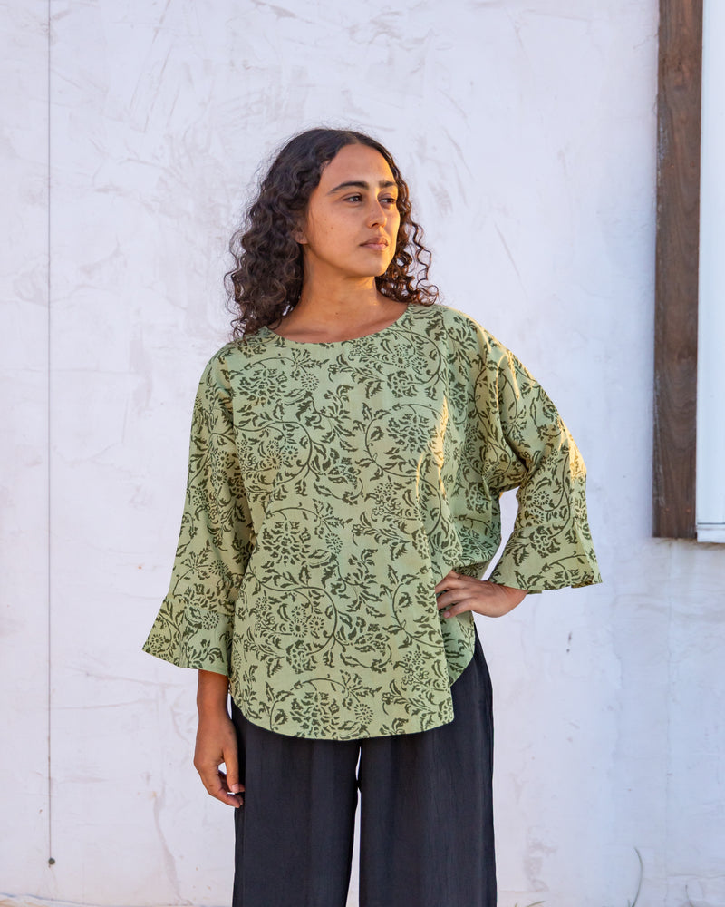 woman dressed in boa flared top in gooseberry print standing in front of a white wall