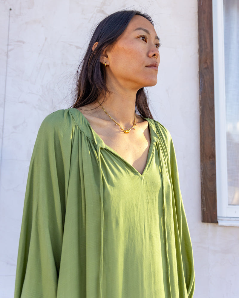 
                  
                    woman dressed in flores organic sugarcane dress in forest green in front of white wall
                  
                