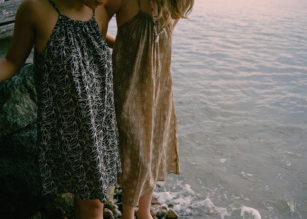 
                  
                    women dressed in beige patterned and black and white patterned midi dresses in front of ocean
                  
                