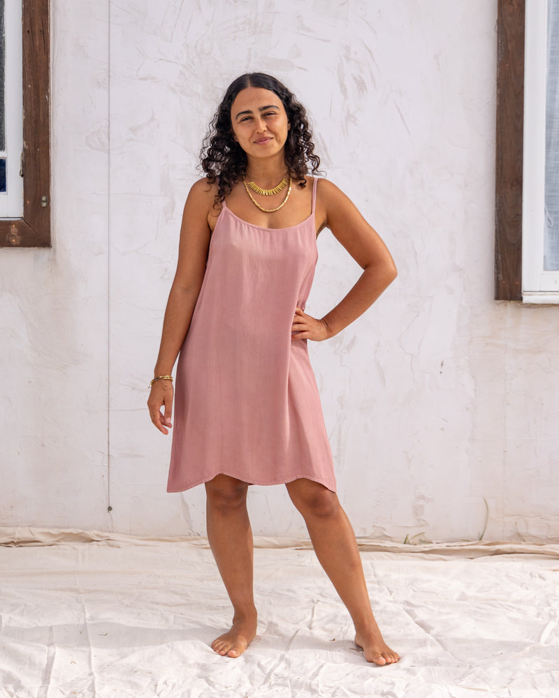 woman dressed in maio mini slip in orange peel fibre in dirty rose pink standing in front of a white wall