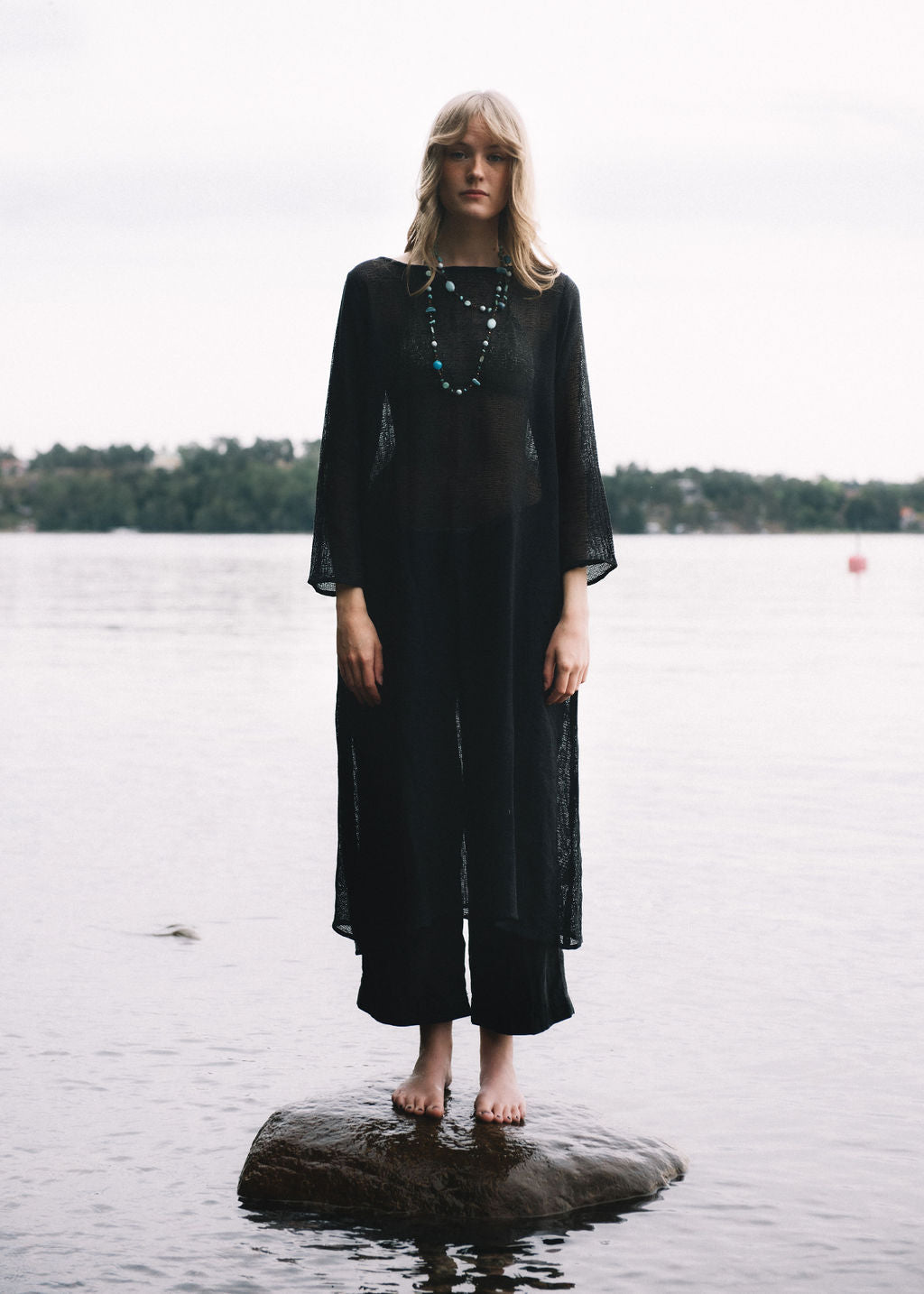 
                  
                    women dressed in netted midi dress in charcoal in front of ocean
                  
                