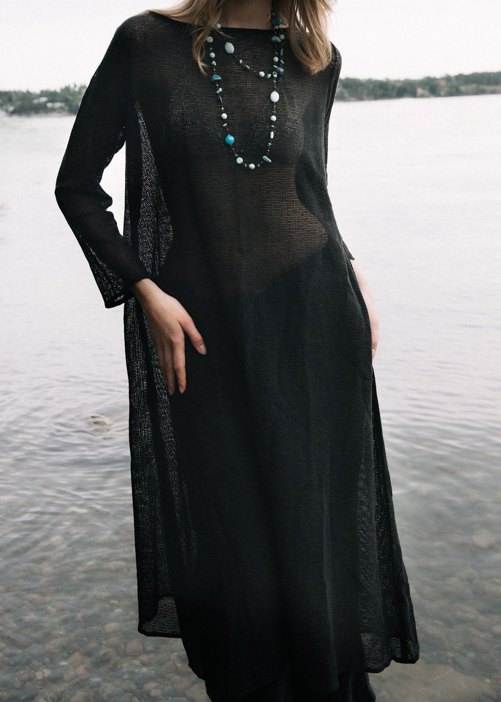 women dressed in netted midi dress in charcoal in front of ocean