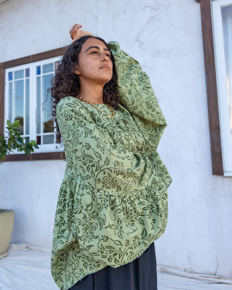 woman dressed in palma billowing sleeves top in gooseberry green print in front of white wall